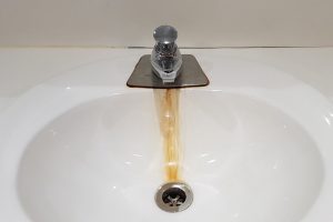 Bathroom sink with a leaky faucet and rust stain in the basin.